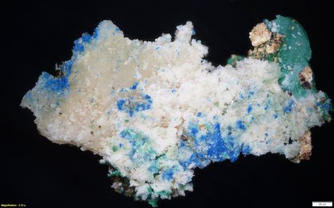 Colour photograph. Magnified photograph of a rock or mineral in vibrant shades of blue, white, and turquoise, showing a close-up view of its surface and texture against a black backdrop. On the lower left yellow text reads, ‘Magnification: 3.15 x’. On the right, a small white rectangle bears the number 200.