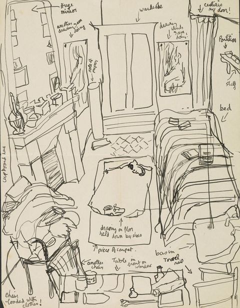Drawing. A busy line drawing describing the view looking down into a crowded bedroom with a bed, wardrobe, fireplace and chair, all of which are scattered with detritus including clothes, art, and art materials. Hand-written notes describe the room contents in more detail. Drawings have been pinned to the wall, with one labelled, ‘drawing which I am doing’.